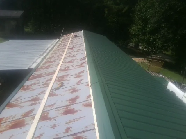 Old rusted panels beside newly installed green metal roofing — Wind Damage Roof Repair by Roofing Brothers in Ash Fork