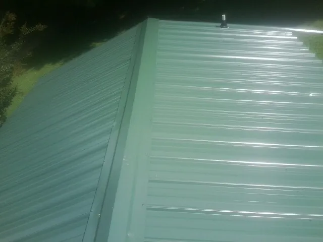 New green metal panels meeting at the ridge of a roof — Flat Roof Repair work by our crew in Ash Fork